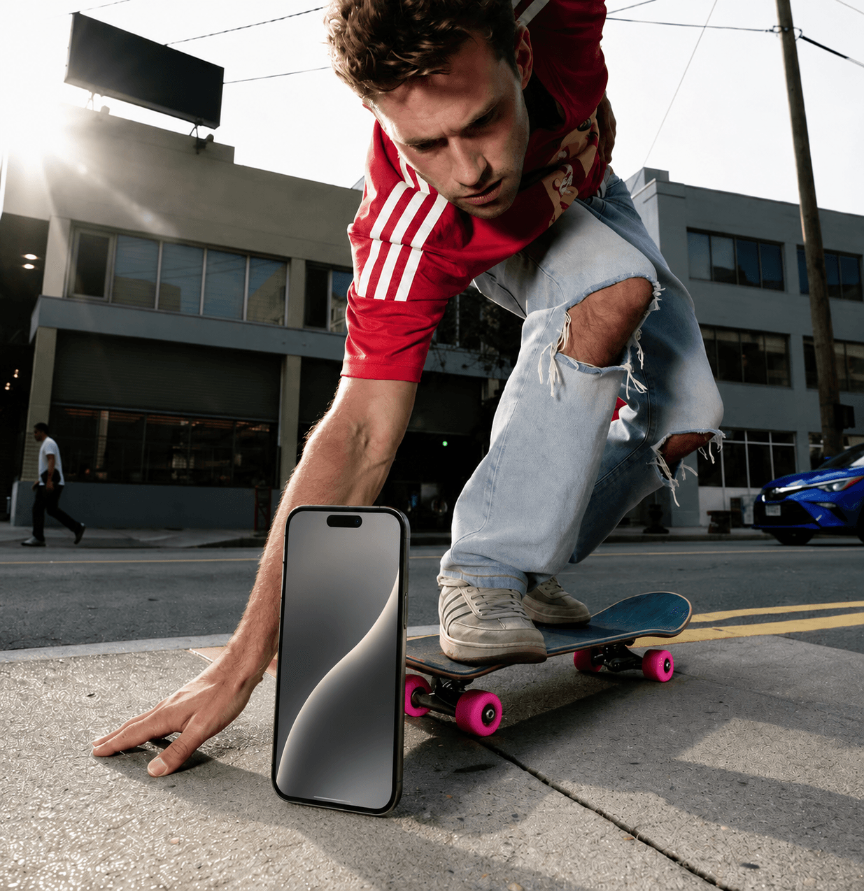 Beispiel-Creative für Instagram Ads: Skateboarder auf einer Stadtstraße greift nach einem Smartphone im Vordergrund – Lifestyle-Motiv für mobile Zielgruppen